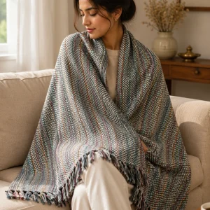 Woman wrapped in grey reversible pashmina blanket on sofa